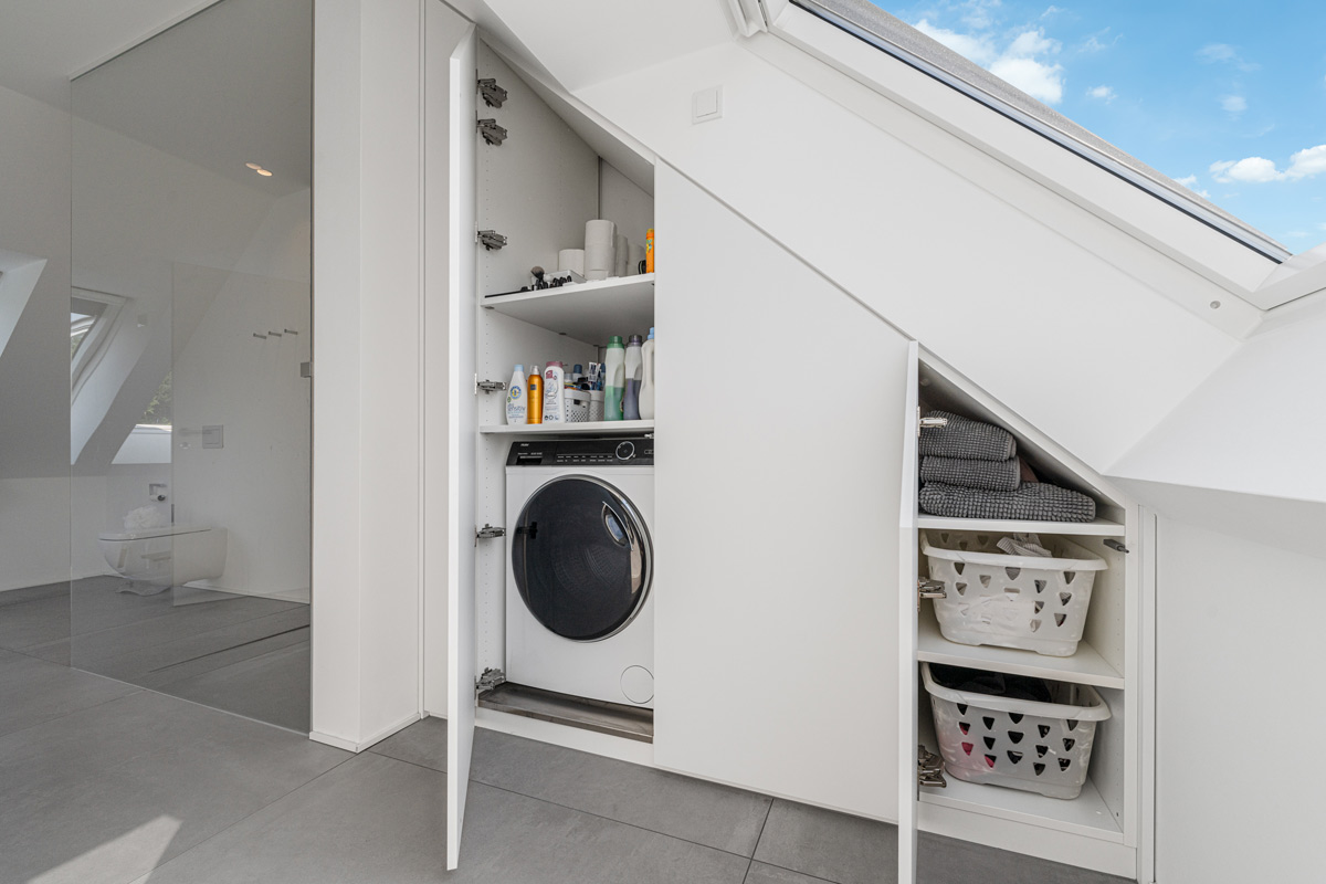 Weißer Schrank nach Maß für die Waschküche in einer Dachschräge integriert